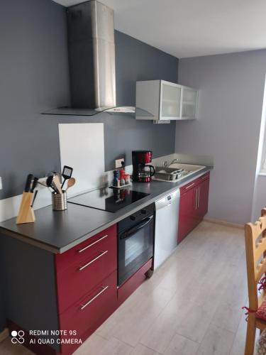 une cuisine avec des armoires rouges et un comptoir noir dans l'établissement L'Arc en ciel, à Gérardmer