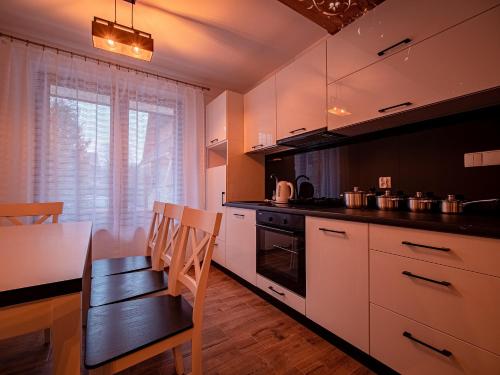 eine Küche mit weißen Schränken, einem Tisch und einem Esszimmer in der Unterkunft Tatrzańska Kryjówka Premium Chalets Zakopane in Poronin