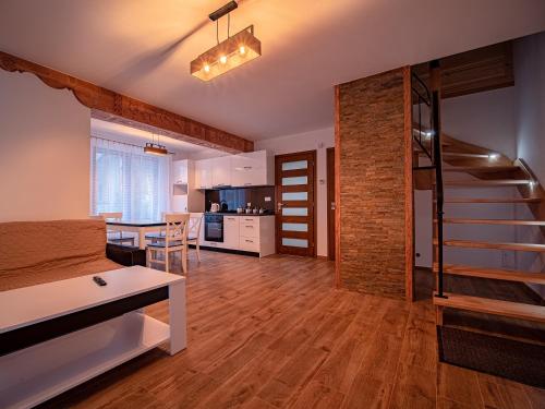 a living room with a staircase and a kitchen at Tatrzańska Kryjówka Premium Chalets Zakopane in Poronin