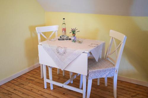 a white table with two chairs and a bottle of wine at Dooscht Gästehaus Reichshof in Kröv