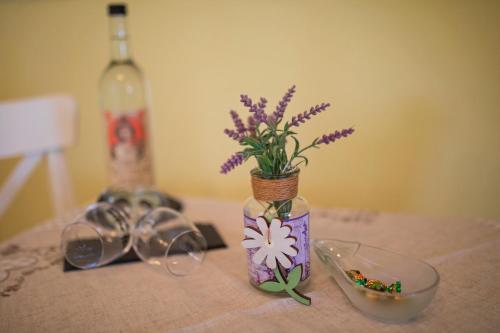 a table with a bottle of wine and a vase with purple flowers at Dooscht Gästehaus Reichshof in Kröv