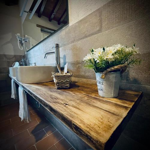 a sink and flowers on a wooden counter in a bathroom at La valle B&B in Cavriglia