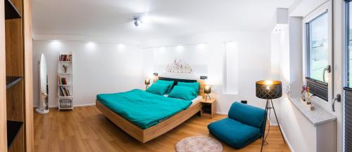 Schlafzimmer mit einem Bett mit blauer Bettwäsche und einem Stuhl in der Unterkunft Zelena dolina in Cerkno