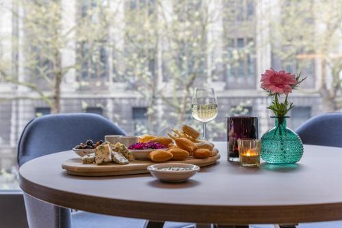 a table with a plate of food and a glass of wine at Postillion Hotel WTC Rotterdam in Rotterdam