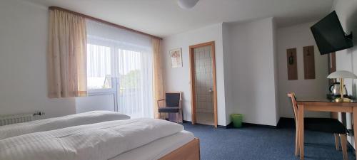 a bedroom with a bed and a desk and a window at Hotel Seehalde in Nonnenhorn