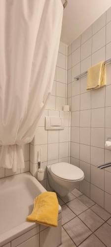 a white bathroom with a tub and a toilet at Hotel Seehalde in Nonnenhorn