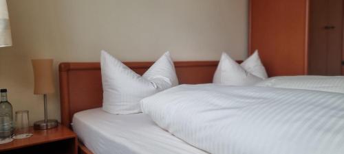 a bedroom with two beds with white sheets and pillows at Hotel Seehalde in Nonnenhorn