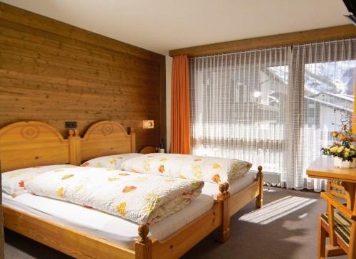 a bedroom with a bed and a large window at Ambiente Guesthouse in Saas-Fee
