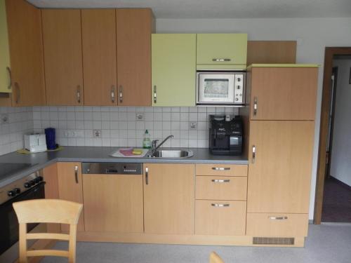 a kitchen with wooden cabinets and a sink and a microwave at Ferienwohnung Schautzgy in Reutte