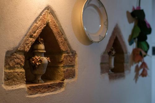 a clock hanging on a wall with a vase on it at Dimora Tipica Toscana in Monticiano