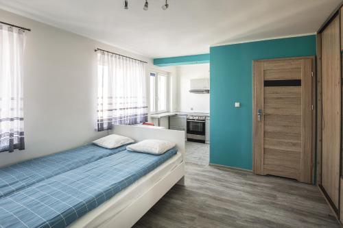 een slaapkamer met een bed en een blauwe muur bij High Floor Vision Apartment in Opole