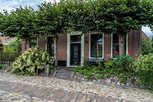 uma casa de tijolos com uma grande árvore em frente em Bij de Friesche Poort em Bourtange