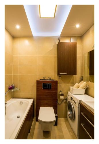 a bathroom with a toilet and a sink and a washing machine at Apartament Jantarowa in Gdynia