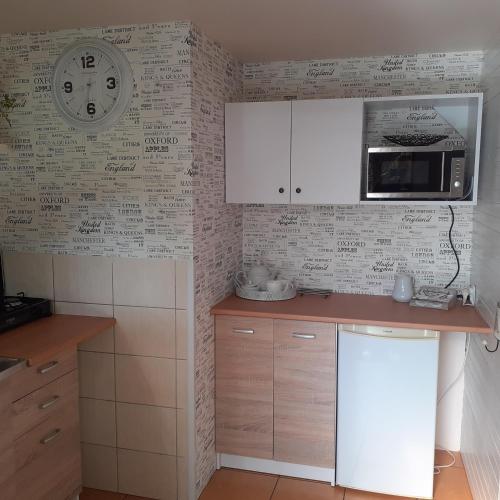 a kitchen with a clock on a wall with writing at domek dla 2 osób in Junoszyno