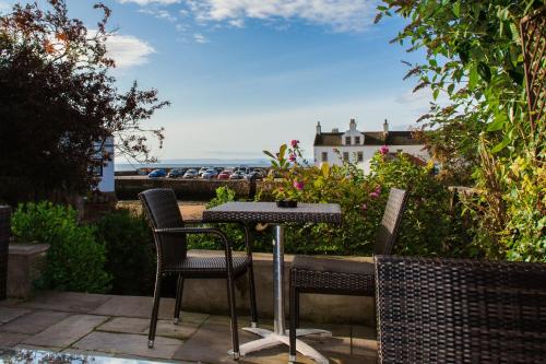 a table and chairs on a patio with a view of the ocean at The Bank in Anstruther