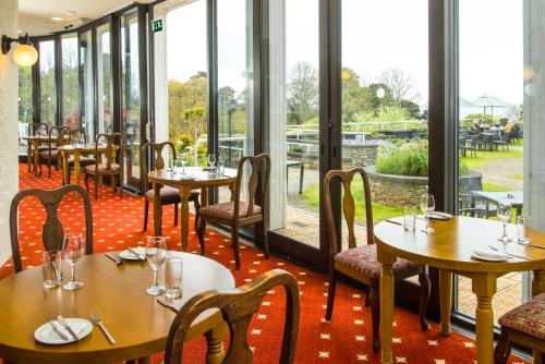 a restaurant with tables and chairs and large windows at Cliffden Hotel in Teignmouth