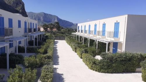 a walkway between two buildings with trees and mountains at Central Apartment Macari Cala Azzurra Residence in Macari