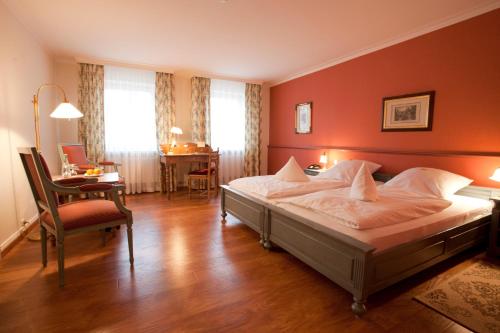 a bedroom with a bed and a desk and a chair at Landhaus Schulze-Hamann - Hotel garni - in Blunk