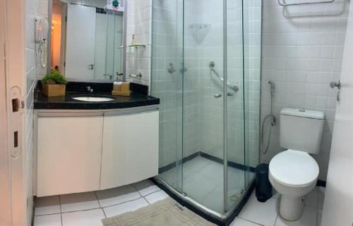 a bathroom with a toilet and a glass shower at Ponta Negra Beach Luxury in Natal