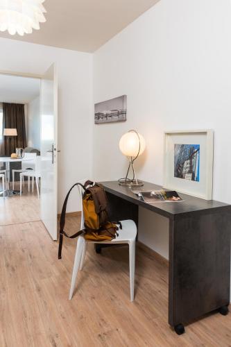 a desk with a bag sitting on a chair in a room at Ténéo Apparthotel Talence - Arthena in Talence
