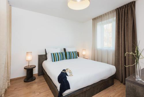 a bedroom with a large white bed and a window at Ténéo Apparthotel Talence - Arthena in Talence