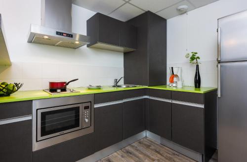 a kitchen with black cabinets and green counter tops at Ténéo Apparthotel Talence - Arthena in Talence