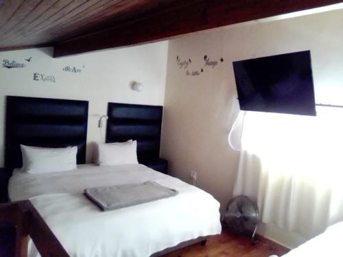 a bedroom with two beds and a flat screen tv at LightStone Guesthouse in Centurion