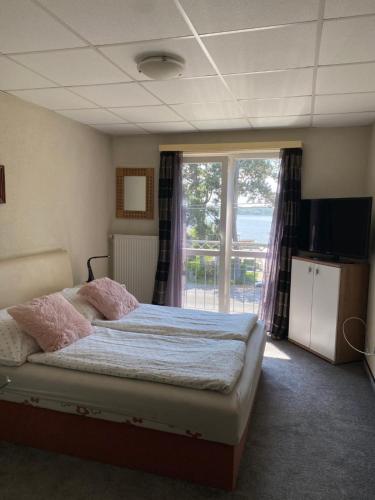a bedroom with a bed and a large window at Panzió Tata in Tata