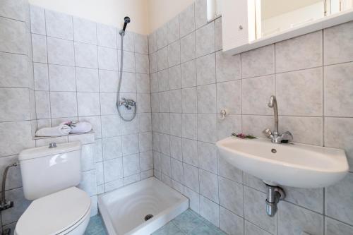 a white bathroom with a toilet and a sink at Mediterraneo studios in Vasiliki