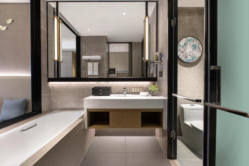 a bathroom with a tub and a sink and a toilet at Ascott Xiangjiang FFC Changsha in Changsha