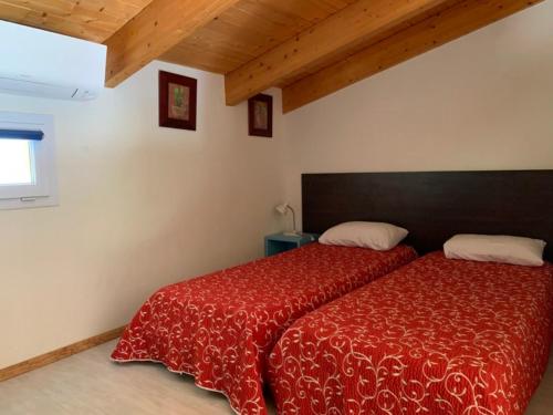 a bedroom with a bed with a red comforter and a window at Les Villas de Lava in Appietto
