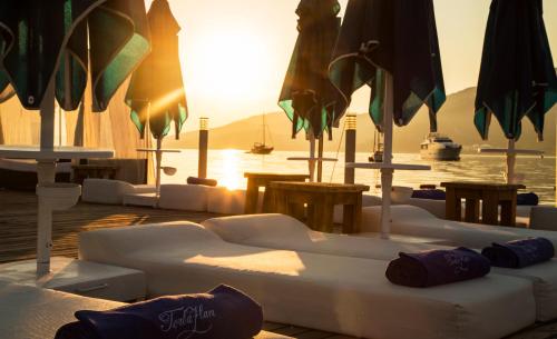 a group of white couches and umbrellas in front of the water at Torbahan Hotel in Torba