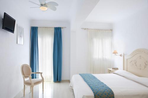 a bedroom with a bed and a chair and a television at Kamari Hotel in Platis Yialos Mykonos