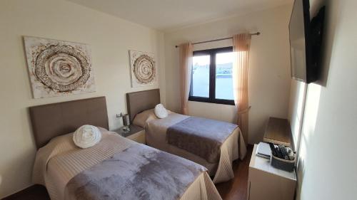 a hotel room with two beds and a window at Villa BELLA on Golf in La Estancia, Caleta Fuste-Fuerteventura in Caleta De Fuste