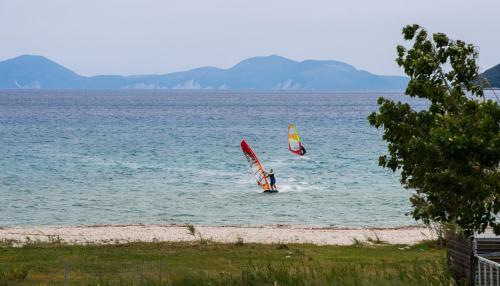 two people windsurfing in the water on a beach at Calypso Luxury Studios in Vasiliki