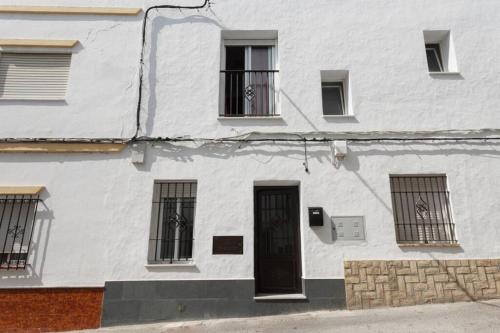a white building with barred windows and a door at PRECIOSO Y PEQUEÑO LOFT CENTRO DE CONIL in Conil de la Frontera