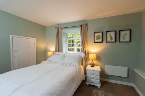 a bedroom with a white bed and a window at Corffe House and Holiday Cottages in Barnstaple