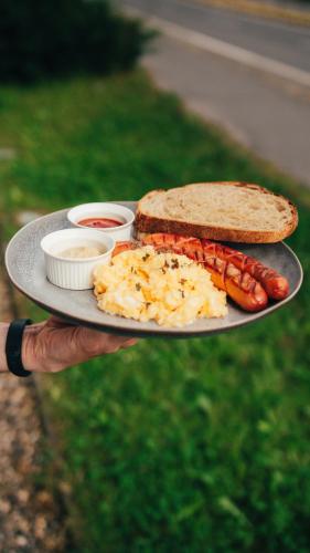 a person holding a plate with hot dogs and a sandwich at Penzion Atlas in Liptovský Mikuláš