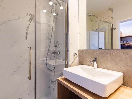 a white bathroom with a sink and a shower at VacationClub - ApartPark Albus Apartament 414 in Świnoujście