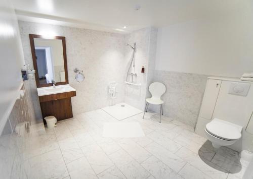 a white bathroom with a toilet and a sink at Hotel Meurice in Calais
