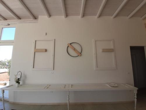una pared blanca con un reloj en la pared en Trullo TerraNostra villa con piscina Torre San Giovanni, en Ugento