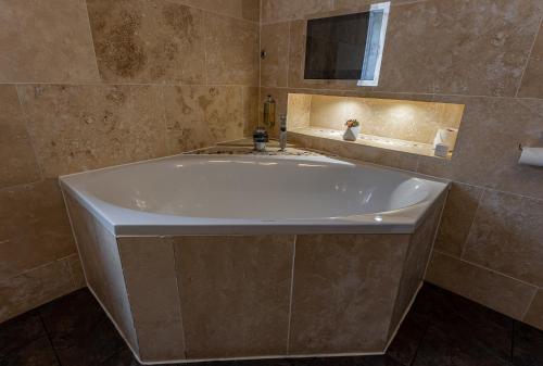 a large white tub in a bathroom with a mirror at Crossways in Wells