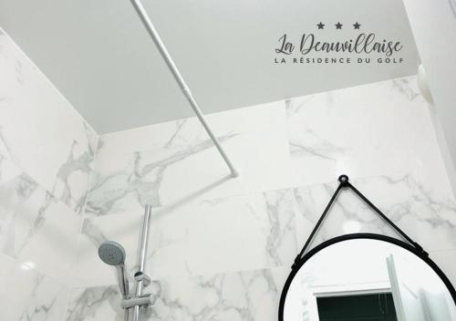 La salle de bains est pourvue d'un miroir et d'un mur en marbre blanc. dans l'établissement La Deauvillaise - Résidence du Golf, à Deauville