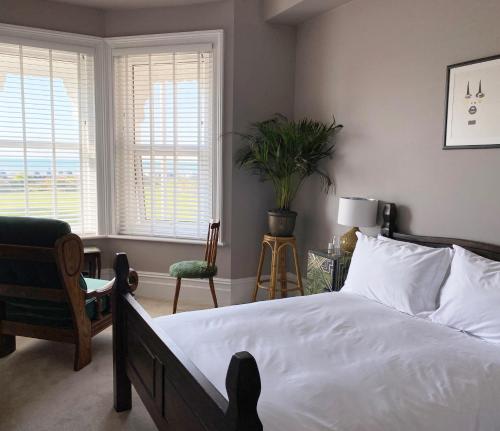 a bedroom with a bed and a chair and windows at 15 Grosvenor in Hastings