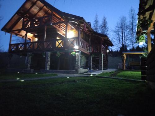 a log home at night with the lights on at Cabana Aura Campulung Moldovenesc in Câmpulung Moldovenesc