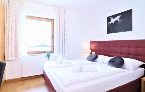 een slaapkamer met een bed met een rood hoofdeinde en een raam bij Chalet Schmittenbach - Pinzgau Holidays in Zell am See