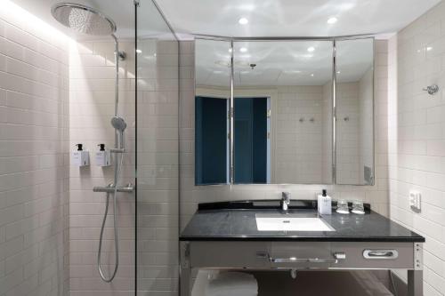 a bathroom with a sink and a shower with a mirror at Scandic Grand Central Helsinki in Helsinki