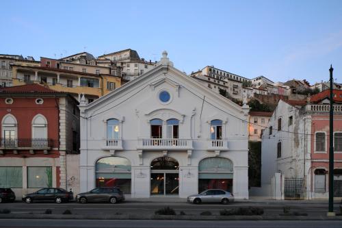 um edifício branco com carros estacionados em frente em Zero Box Lodge Coimbra em Coimbra