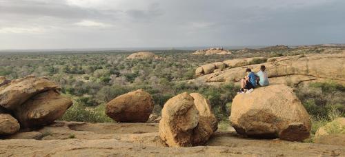 two people sitting on top of a rock at Ai Aiba - The Rock Painting Lodge in Omaruru
