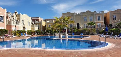 une grande piscine avec des palmiers et des bâtiments dans l'établissement Arenita Apartment, à Palm-mar